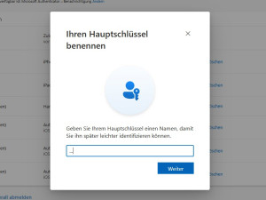 Screenshot eines Microsoft-Dialogfensters mit dem Titel „Ihren Hauptschlüssel benennen“. Es enthält ein Eingabefeld und den Hinweistext: „Geben Sie Ihrem Hauptschlüssel einen Namen, damit Sie ihn später leichter identifizieren können“.